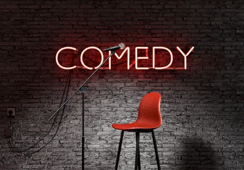 A microphone stand and a red stool in front of a brick wall with a neon sign reading 